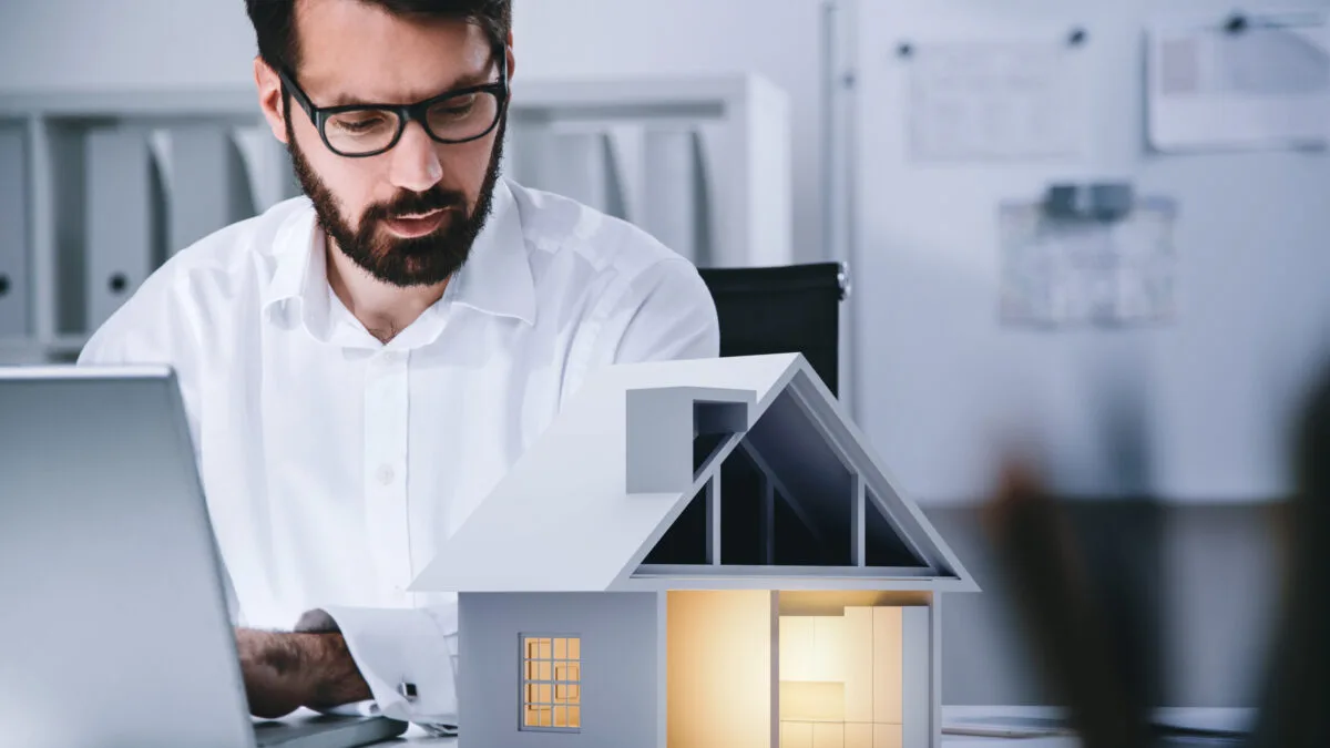 Man on Laptop with Paper House Adobe Stock 517456136