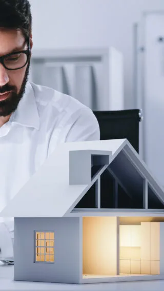 Man on Laptop with Paper House Adobe Stock 517456136